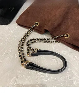 Detail of metal chain and leather shoulder strap on a brown suede bucket bag