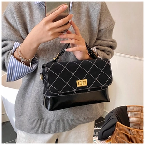 Detail of black quilted handbag with matte and glossy leather textures and gold clasp