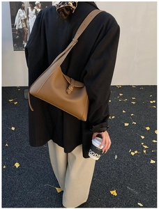 Vue détaillée d'un sac à bandoulière en cuir marron grainé porté par un mannequin en automne
