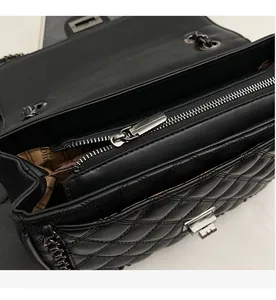 Detail of internal smooth zipper and silver hardware on black quilted crossbody bag