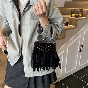Detail of vintage black handbag featuring silver rivets and long fringe tassels decoration