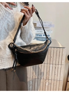 Détail du sac demi-lune en cuir noir avec chaîne dorée et fermeture éclair à franges
