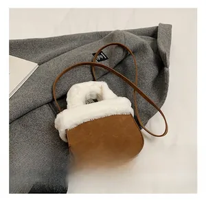 Detail view of winter brown suede bucket bag with fluffy white plush trim and handles