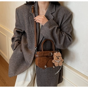 Détail d'un sac bandoulière marron en suédine avec ruban et charm ours peluche