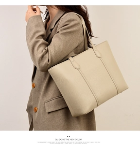 Gros plan sur un sac cabas beige en cuir grainé porté à l'épaule par un mannequin