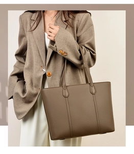 Gros plan d'un sac cabas en cuir marron à motif litchi porté par un mannequin