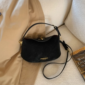 Classic black leather underarm bag with gold buckle and fashion logo on beige background