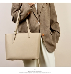 Chic cream tote bag with pebble leather texture styled with a professional brown suit