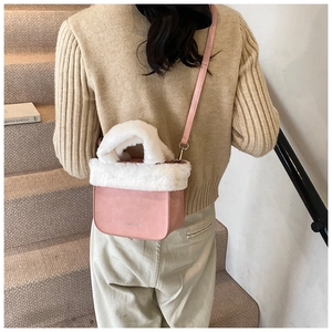 Model wearing a pink faux leather bucket bag with white plush trim on steps