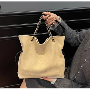 Detail of beige suede bucket bag showing chain strap and drawstring closure mechanism