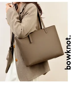 Detail of dark khaki tote bag in pebble grain leather worn over the shoulder for commute
