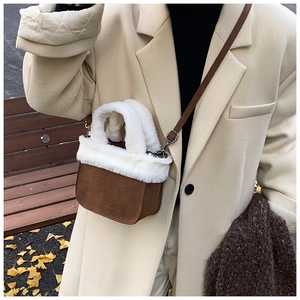 Detail of winter suede bucket bag with white plush faux fur trim and leather strap