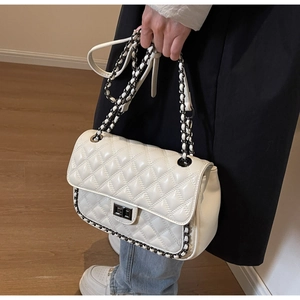 Detailed view of white quilted faux leather shoulder bag with gold metal twist lock and chain strap
