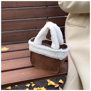 Detailed close-up of winter faux fur trim and suede fabric on a brown bucket bag