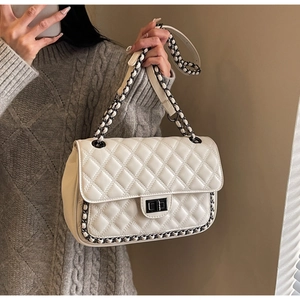 Detail view of the quilted cream leather texture and silver chain strap on the shoulder bag