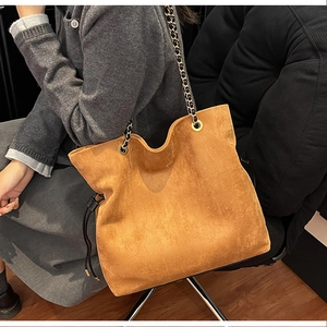Detailed view of caramel suede tote bag with chain strap shown on model for size