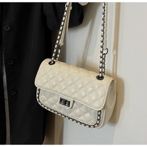 Detail of quilted creamy white bag featuring black chain trim and a square twist lock