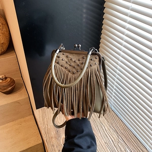 Vintage green suede handbag with fringe tassels and metal studs in atmospheric lighting