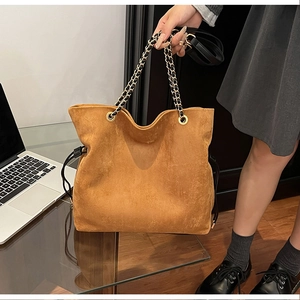 Detail of large ginger suede tote bag with chain strap and drawstring closure