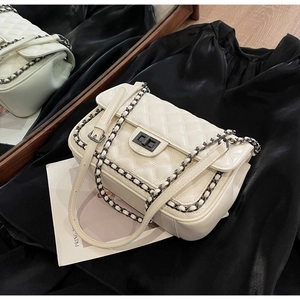 Close-up of beige quilted texture with black metal chain edges and rotary twist lock