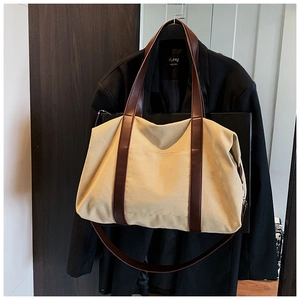 Detail of canvas tote bag with brown leather straps and front pocket for daily use