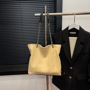 Detail of beige suede tote bag featuring black drawstrings and golden chain straps