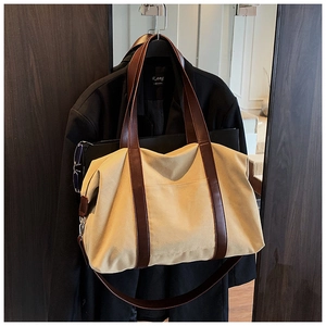Detailed close-up of a canvas tote bag with brown leather straps and metal hardware hooks