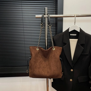 Close-up of brown suede tote bag with drawstring detail and gold chain strap