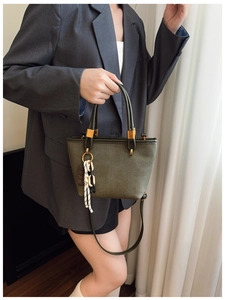 Olive green canvas handbag detail with leather handles and decorative chain accessory