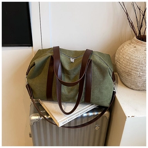 Detail of olive green canvas travel bag with leather handles and metallic zipper closures