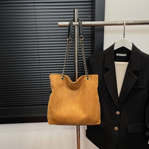 Close-up of brown suede tote bag with leather and metal chain shoulder strap detail
