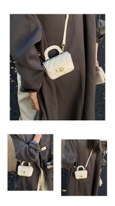 Vertical view of beige quilted mini bag with gold twist lock and crossbody chain strap