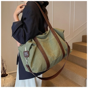 Olive green canvas tote with brown leather straps shown on a model in a minimal interior