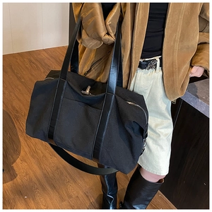 Black canvas tote bag with leather straps and silver hardware shown in a lifestyle scene