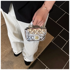 Close-up of mini silver quilted handbag featuring a gold metallic twist lock and handle