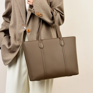 Sac fourre-tout minimaliste en cuir marron foncé avec texture grainée sur un modèle
