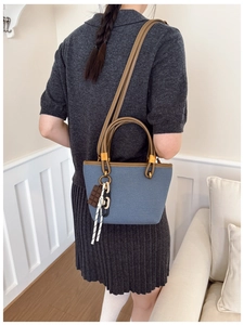 Detail of navy canvas handbag with brown leather trim and chocolate shaped charm decoration