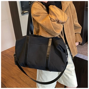 Detail of a large black canvas tote bag showing the texture, handle, and adjustable shoulder strap