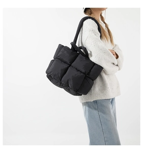 Vue détaillée d'un sac cabas noir matelassé avec des bretelles rembourrées sur un mannequin