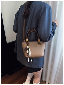 Brown canvas bucket bag with leather handles and chocolate charm shown on model