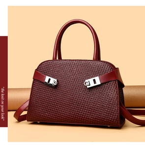 Détail d'un sac à main bordeaux texturé avec boucles métalliques et bandoulière