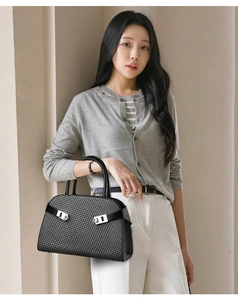 Détail du sac à main noir à texture tissée avec des boucles métalliques en forme de mors