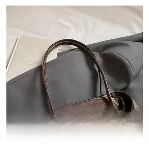 Detail view of slender double handles and vintage oil wax leather texture on the brown tote
