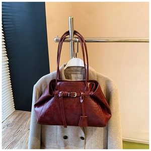 Detail of dark red vintage faux leather tote bag with buckles and hanging ornament