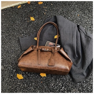 Detail of vintage brown tote bag with leather straps on a stylish grey blazer background