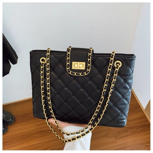 Détail macro du sac bandoulière matelassé noir avec chaîne dorée et fermoir rotatif