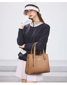 Detail of brown leather tote bag showing lychee grain texture and metal buckle handle