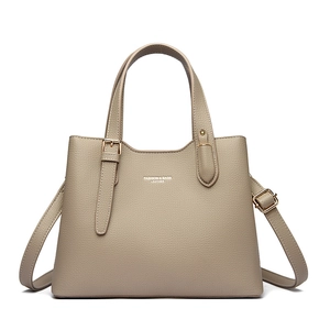 Detailed macro of khaki lychee grain leather tote bag with gold metal buckle and handle