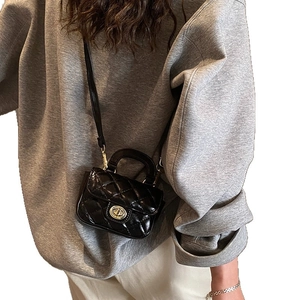 Mini black quilted handbag with chain strap shown on model against a white background