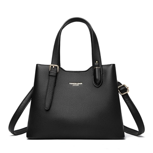 Close-up of black lychee grain leather tote bag with gold logo and hardware details